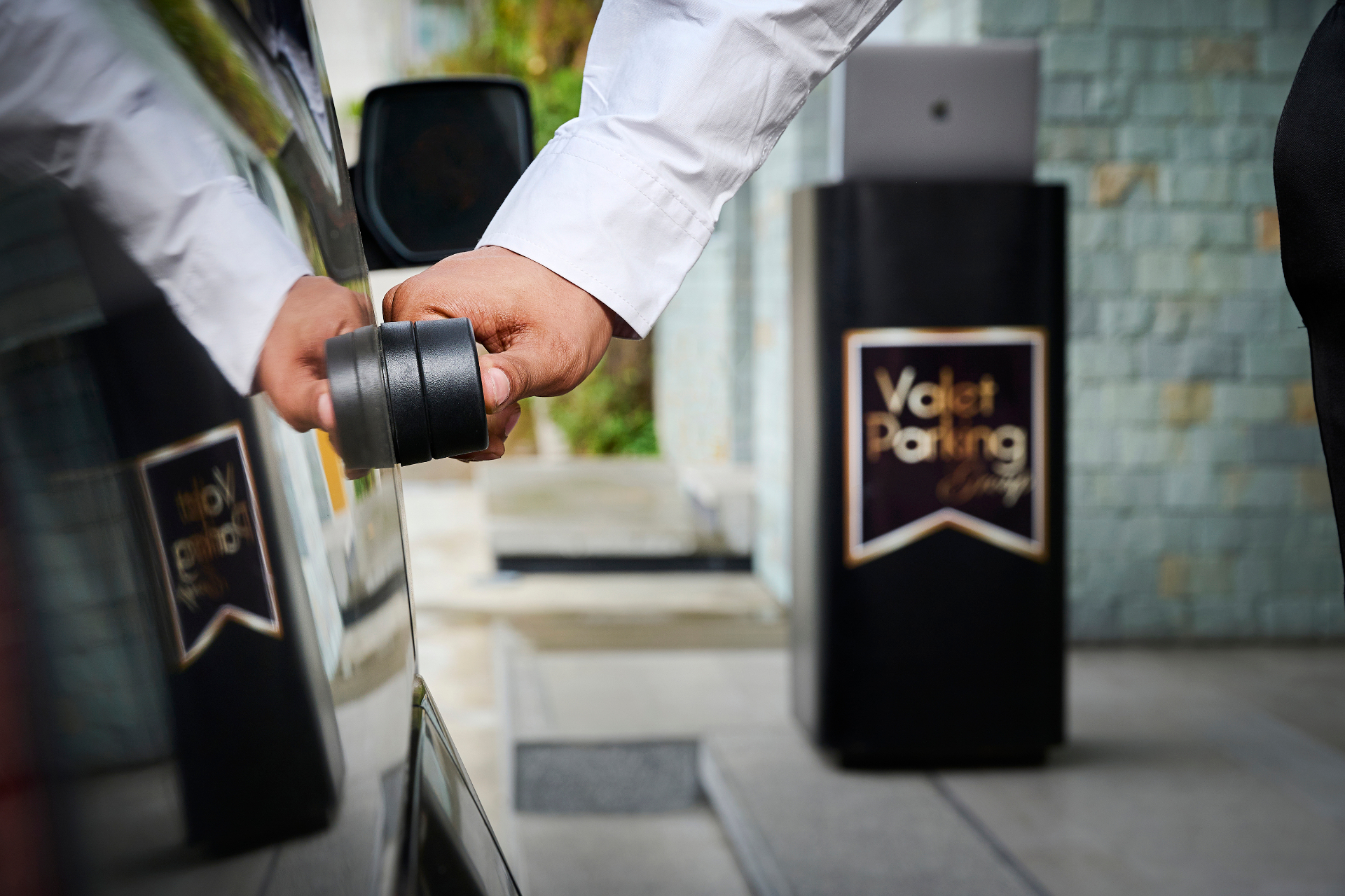 Valet parking premium recibiendo un automóvil de lujo en la entrada de un hotel