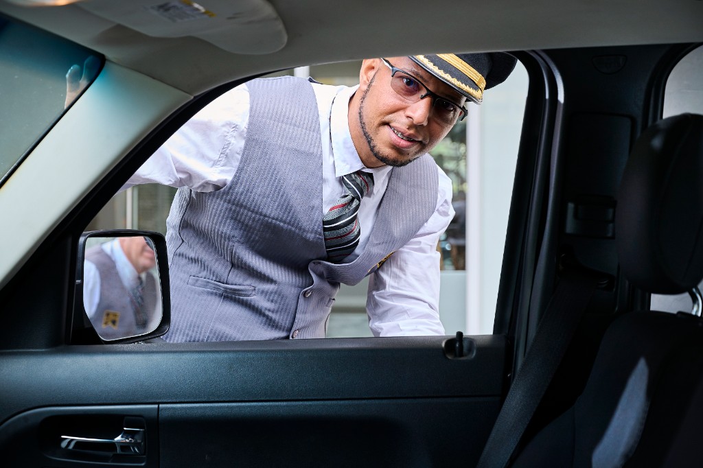 Valet atendiendo al cliente desde la ventanilla del vehículo